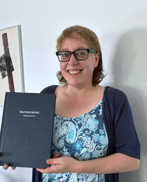 Foto von mir mit ausgedruckter Bachelorarbeit in der Hand und strahlendem Lächeln